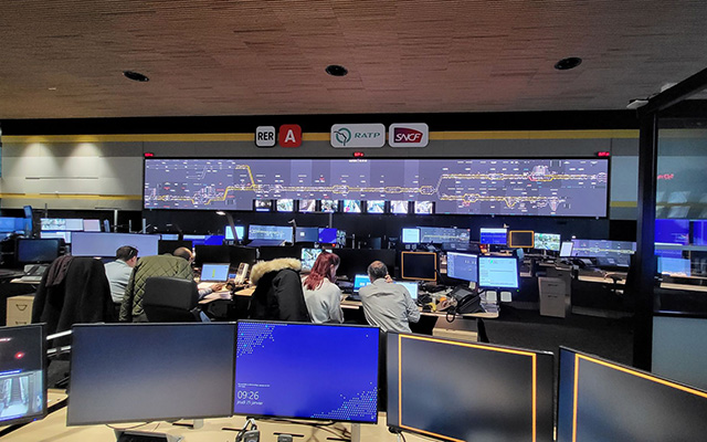 a busy control room with desktop monitors and a very wide LED videowall